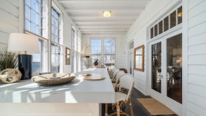 A long dining table with wicker chairs, large windows, and a view of the outdoors. - Delightful 6-bedroom cottage on charming Lake Carlos in Alexandria, MN (Alexandria)