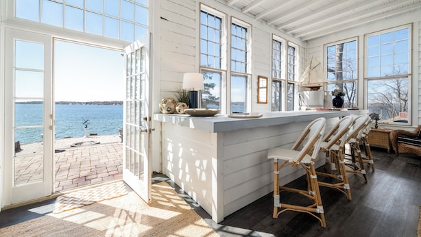A spacious kitchen with large windows, a bar area with high stools, and a view of the water. - Delightful 6-bedroom cottage on charming Lake Carlos in Alexandria, MN (Alexandria)