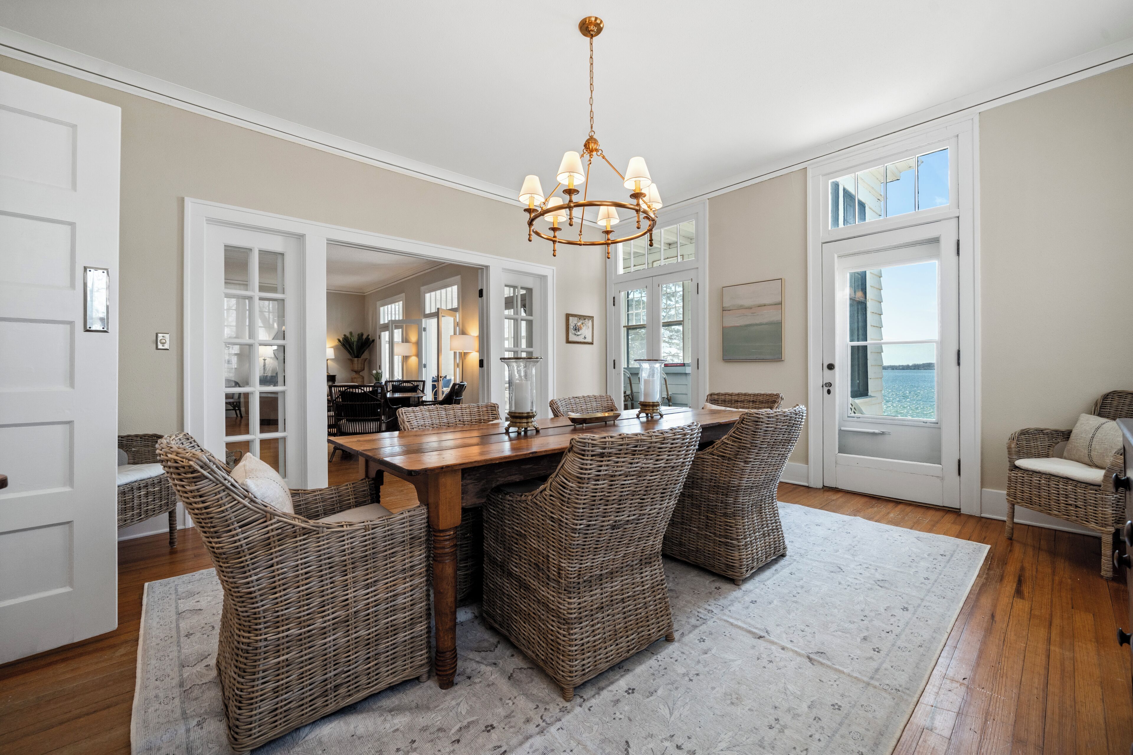 A dining area with wicker chairs, a wooden table, and a chandelier.