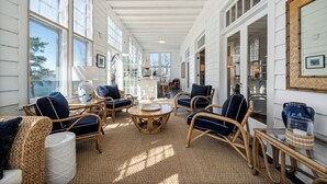 A spacious room with large windows, wicker furniture, and a central round table. - Delightful 6-bedroom cottage on charming Lake Carlos in Alexandria, MN (Alexandria)