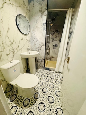 Een badkamer met toilet, wastafel en douche.