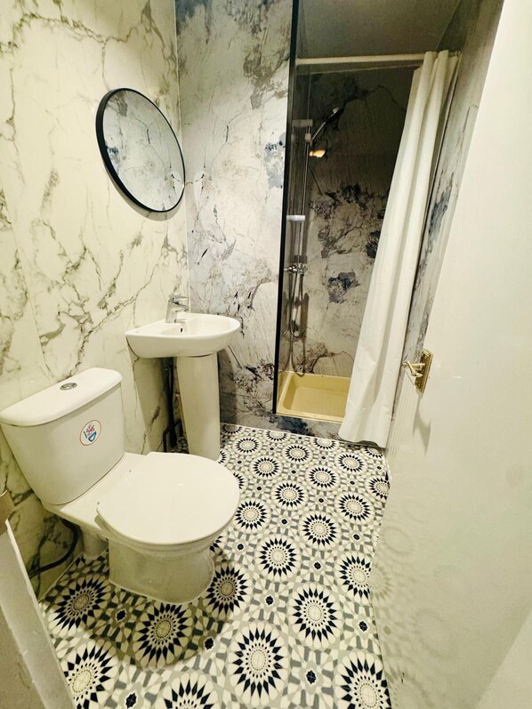 Un baño con inodoro, lavamanos y ducha.