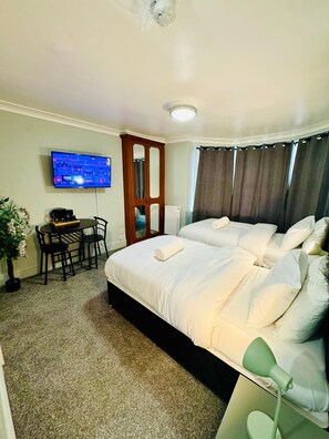 Una habitación de hotel con una cama, un escritorio con una silla, un televisor y una planta en maceta.