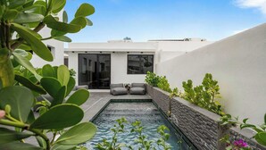 A modern outdoor pool area with a stone wall, seating, and greenery. - Modern Villa - Private Pool & Rooftop Terrace (San Juan)