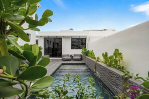 A modern outdoor pool area with a stone wall, seating, and greenery. - Modern Villa - Private Pool & Rooftop Terrace (San Juan)