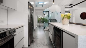 A modern kitchen with a central island, stainless steel appliances, and a view to the outdoors. - Modern Villa - Private Pool & Rooftop Terrace (San Juan)