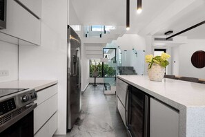 A modern kitchen with a central island, stainless steel appliances, and a view to the outdoors. - Modern Villa - Private Pool & Rooftop Terrace (San Juan)