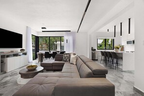 A modern living room with a sectional sofa, a round coffee table, and a flat-screen TV. - Modern Villa - Private Pool & Rooftop Terrace (San Juan)
