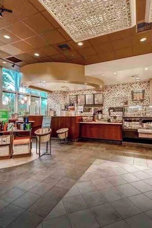 Ein geräumiges Café-Interieur mit einer Holztresen, Fliesenböden und einer dekorativen Decke.