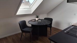 A dining area with a round table, two chairs, a potted plant, and a skylight. - Vacation apartment Reinhardt (Nidda)
