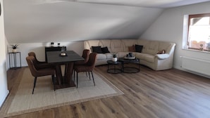A modern loft with a dining area, a sofa, and a window. - Vacation apartment Reinhardt (Nidda)