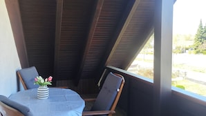 A covered patio area with a table and two chairs, a vase with flowers, and a view of the outdoors. - Vacation apartment Reinhardt (Nidda)