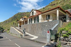 Un edificio su due piani con un muro in pietra, un balcone e una scala che conduce al piano superiore.