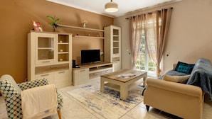 A living room with a sofa, a coffee table, a TV, and a cabinet. - Holiday Home 'Jardim do Sol' with Sea View, Private Garden and Wi-Fi (Lugares)