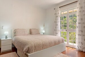 A bedroom with a bed, nightstands, and a window with curtains. - Holiday Home 'Jardim do Sol' with Sea View, Private Garden and Wi-Fi (Lugares)