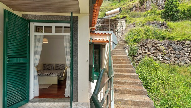 A staircase leading to a room with a bed and a window with green shutters. - Holiday Home 'Jardim do Sol' with Sea View, Private Garden and Wi-Fi (Lugares)