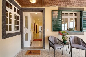 A hotel lobby with a double door, two chairs, a small table, and a potted plant. - Holiday Home 'Jardim do Sol' with Sea View, Private Garden and Wi-Fi (Lugares)