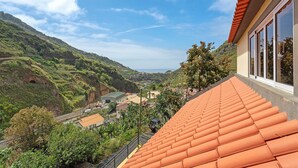 A hillside view with a building featuring a terracotta roof and large windows. - Holiday Home 'Jardim do Sol' with Sea View, Private Garden and Wi-Fi (Lugares)