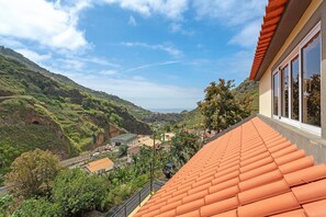 Panorama su una collina con tegole in terracotta, un edificio con ampie finestre e una valle verdeggiante con edifici.