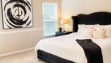 A bedroom with a bed, a ceiling fan, a window with blinds, and a wall art piece.
