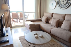 Ein Wohnzimmer mit einer Couch, einem Couchtisch mit Kerzen, einem Fernseher und einer Lampe.