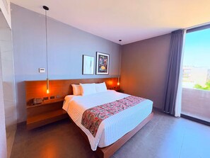 Ein modernes Hotelzimmer mit einem großen Bett, einem Nachttisch, einer Wandleuchte und einem mit Vorhängen versehenen Fenster.