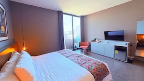Habitación de hotel con cama, televisor, escritorio y una silla.