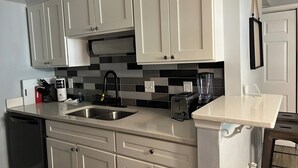 A modern kitchen with white cabinets, a black and gray backsplash, a sink, a toaster, and a blender. - On Island | Pool | Tennis | Pet Friendly | Parking (Hilton Head Island)