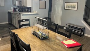 A dining area with a wooden table, chairs, a metal basket, and a red folder on the table. - On Island | Pool | Tennis | Pet Friendly | Parking (Hilton Head Island)