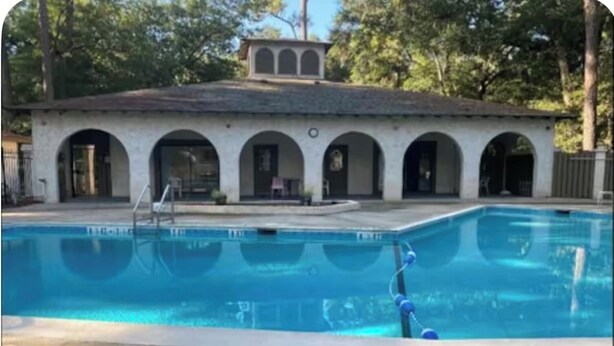 A swimming pool with a clear water surface, a lifeguard stand, and a building with arched doorways in the background. - On Island | Pool | Tennis | Pet Friendly | Parking (Hilton Head Island)