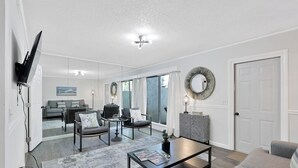 Una sala de estar moderna con un sofá, sillones, una mesa de centro y un televisor montado en la pared.