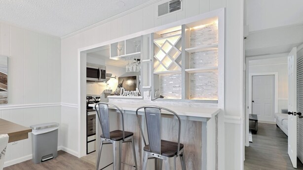 Una cocina moderna con barra, armarios blancos y un salpicadero decorativo.