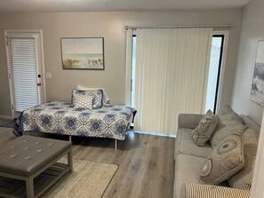 Ein Schlafzimmer mit Bett, Bank, Sofa und einer Tür mit Jalousien.