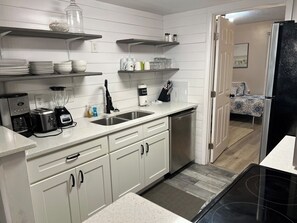 Cozinha compacta com armários brancos, lava-louças, cafeteira e liquidificador.