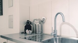 A modern kitchen with a stainless steel sink, a coffee machine, and a utensil holder. - LU Mercury lll - Old Town HITrental Apartment by Interhome (Lucerne)