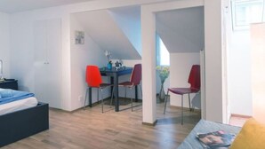 A modern interior with a bed, a dining table with chairs, and a kitchen area. - LU Mercury lll - Old Town HITrental Apartment by Interhome (Lucerne)