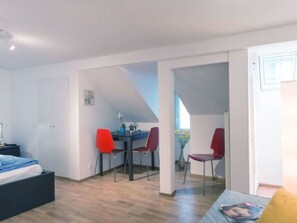 En modern inredning med en säng, ett matbord med stolar och ett köksområde.