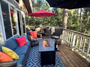 A deck with a sofa, chairs, a table, and a fire pit.