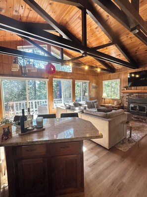 Amplia sala de estar con un ventanal grande, una chimenea y una zona de cocina con encimera de madera.