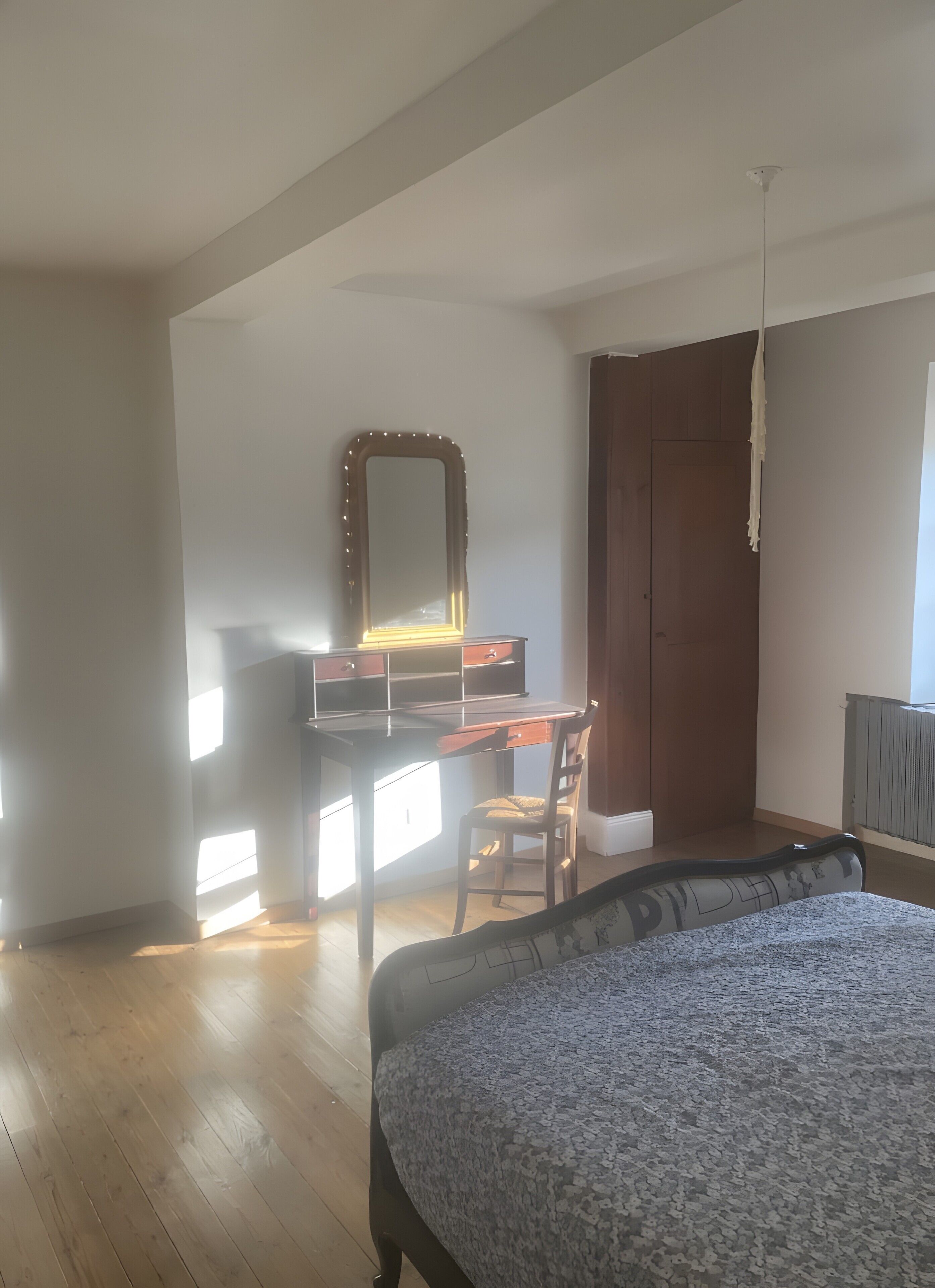Une chambre à coucher avec un lit, un bureau doté d’un miroir, une chaise et une armoire.