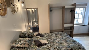 Une chambre à coucher avec un lit, une armoire, un miroir et une fenêtre.