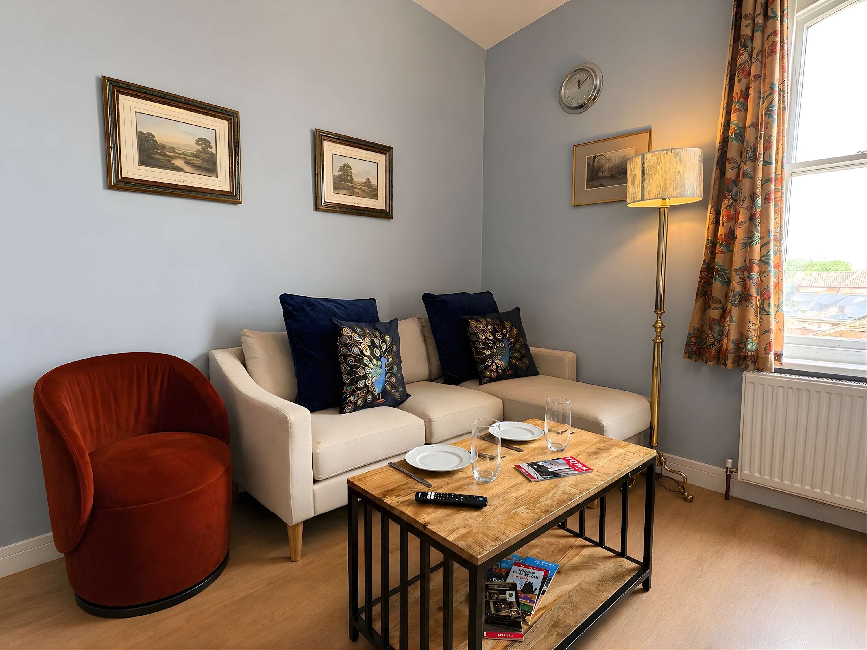 Ein Wohnzimmer mit Sofa, Sessel, Couchtisch, gerahmten Bildern und einer Lampe.