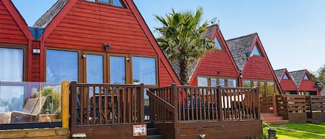 A row of red-roofed cabins with wooden decks and windows.