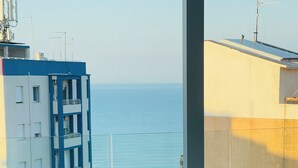 Habitación de hotel moderna con un amplio ventanal que da a una masa de agua y un edificio.