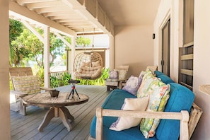 A covered outdoor seating area with a wooden table, a hanging chair, and a sofa with patterned cushions. - Le Rêve -Beachfront 5BR Luxury Villa w/ Private Pool, Dock & 5 Min to Town (San Pedro)