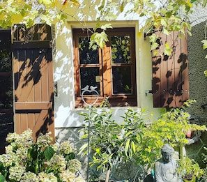 A house with a wooden door, a window with a heart-shaped decoration, and a statue in the garden. - Quite country retreat, close to villages but very peaceful (Terres-de-Haute-Charente)