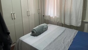 Huone, jossa on sänky, vaatekaappi ja ikkuna, jossa on verhot.