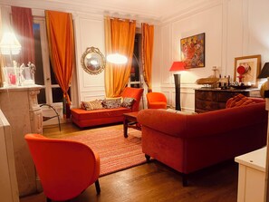 Ein Wohnzimmer mit einer Couch, Sesseln, einer Lampe und einem Bild an der Wand.