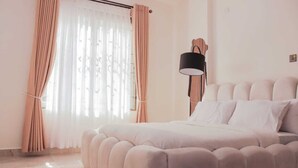 Una camera da letto con un letto grande, una lampada a parete e tende leggere.