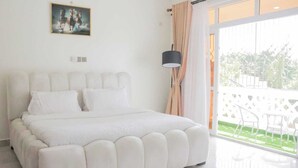 Una camera da letto con un letto grande, un quadro appeso al muro, una lampada e vista sull'esterno.